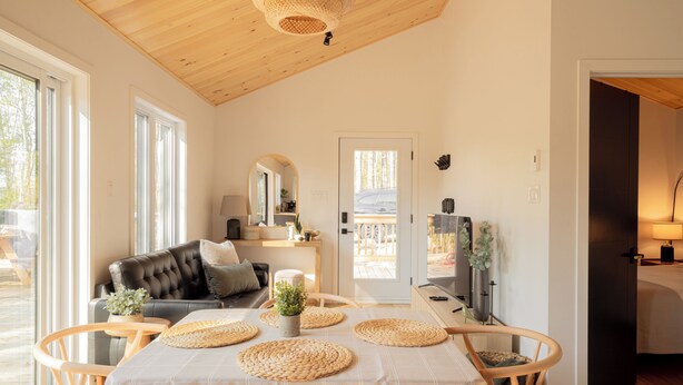 Ein gemütliches Zimmer mit Esstisch, Stühlen, einer Couch und einem Fernseher.