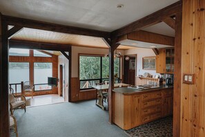 A spacious room with large windows, a wooden dining area, and a kitchen with wooden cabinets.