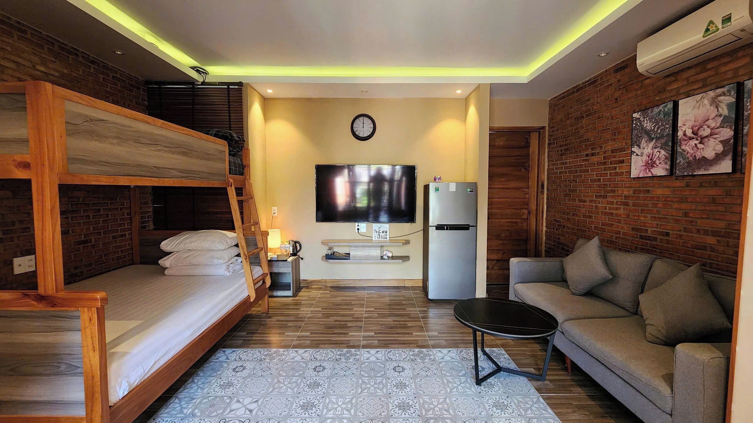 A compact living space with a bunk bed, a sofa, a TV, a refrigerator, and a patterned rug.