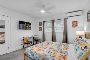 Ein Hotelzimmer mit Bett, Schreibtisch, zwei Stühlen, einem Stadtbild und einem Fenster mit Vorhängen.