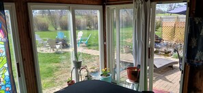 Een kamer met uitzicht op een achtertuin, een patio en een houten terras.
