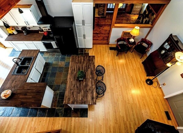 Una cucina moderna con isola centrale, zona pranzo con due sedie e un piccolo tavolo con lampada.