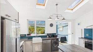 Eine moderne Küche mit Geschirrspüler, Waschmaschine und Blick auf die Landschaft durch große Fenster.