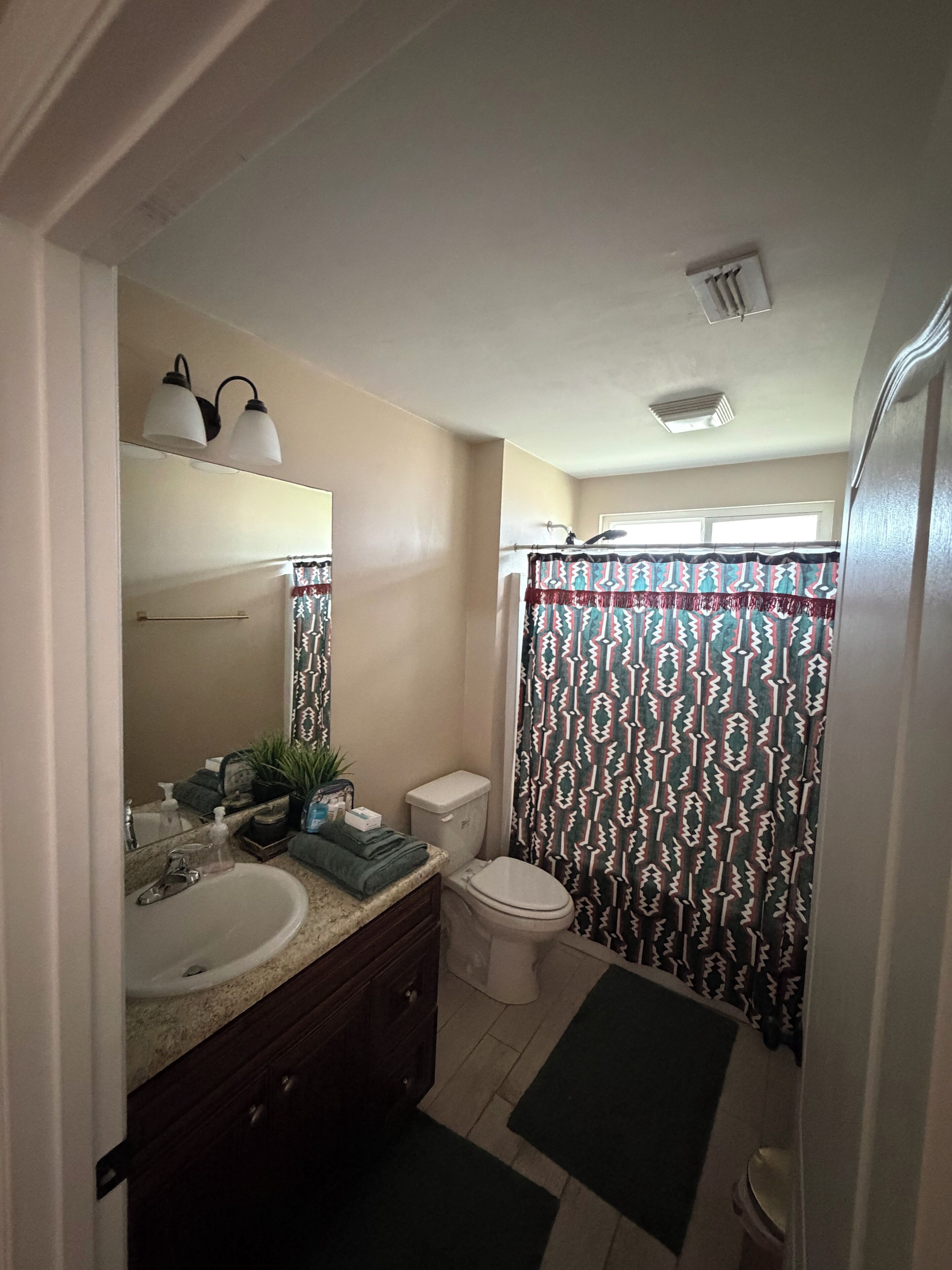 Un bagno con lavandino, specchio, water e tenda per la doccia.