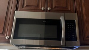 A kitchen with a built-in microwave, wooden cabinets, and a glass-top table. - Spacious 2BR 2BA Near FSU, FAMU & Downtown (Tallahassee)