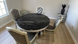 Un comedor con una mesa redonda, cuatro sillas y una decoración de piña.