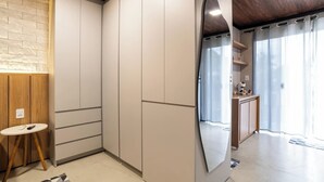 A modern bedroom with a large wardrobe, a round mirror, a small round table, and a wooden accent wall. - Studio for Work and Relaxation | Pool + AC | Pet Friendly | Novo Hamburgo (Novo Hamburgo)