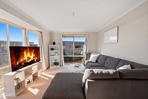 A modern living room with a fireplace, a sofa set, and a television. - Granton River Views Near Hobart Cozy Retreat (Granton)