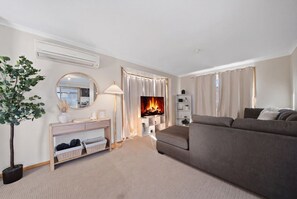 A modern living room with a sofa, a fireplace, a mirror, and a plant. - Granton River Views Near Hobart Cozy Retreat (Granton)
