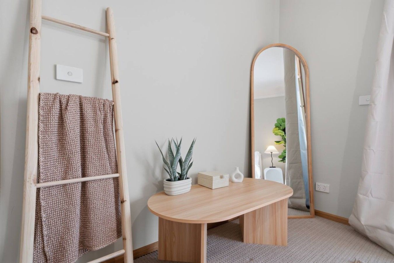 A bathroom with a wooden vanity, a mirror, a towel rack, and a potted plant.