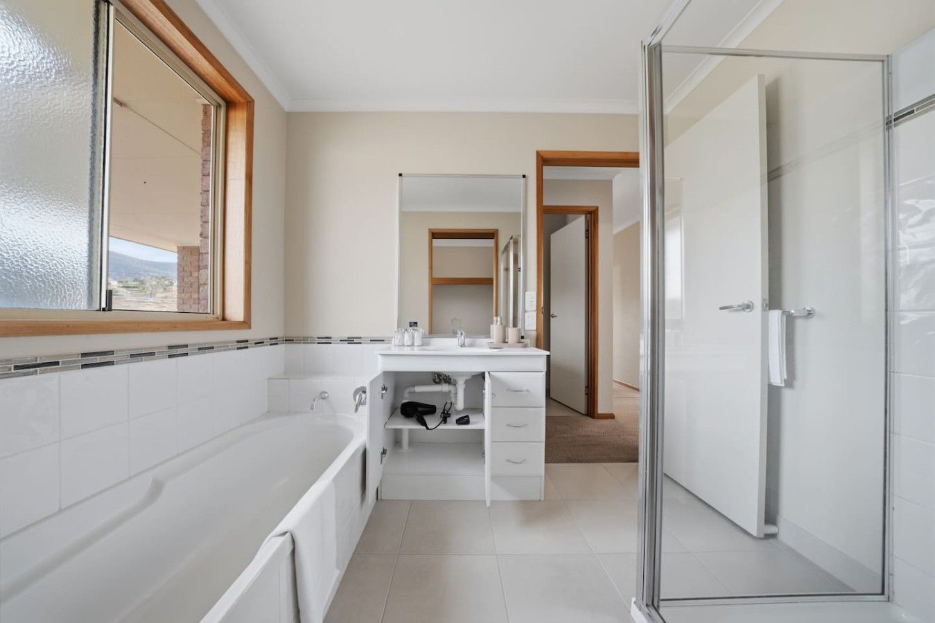 Ein modernes Badezimmer mit Badewanne, Waschtisch mit Spiegel und Duschbereich.