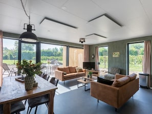 Ein geräumiges Wohnzimmer mit großem Fenster, Essbereich und einer Couch.