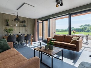 Ein zeitgemäßer Wohnbereich mit Sofa, Couchtisch und Essbereich, ausgestattet mit großen Fenstern und Blick ins Freie.