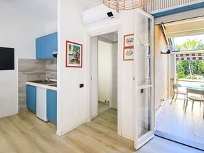 A kitchen with blue cabinets, a white countertop, and a dining area with a table and chairs.