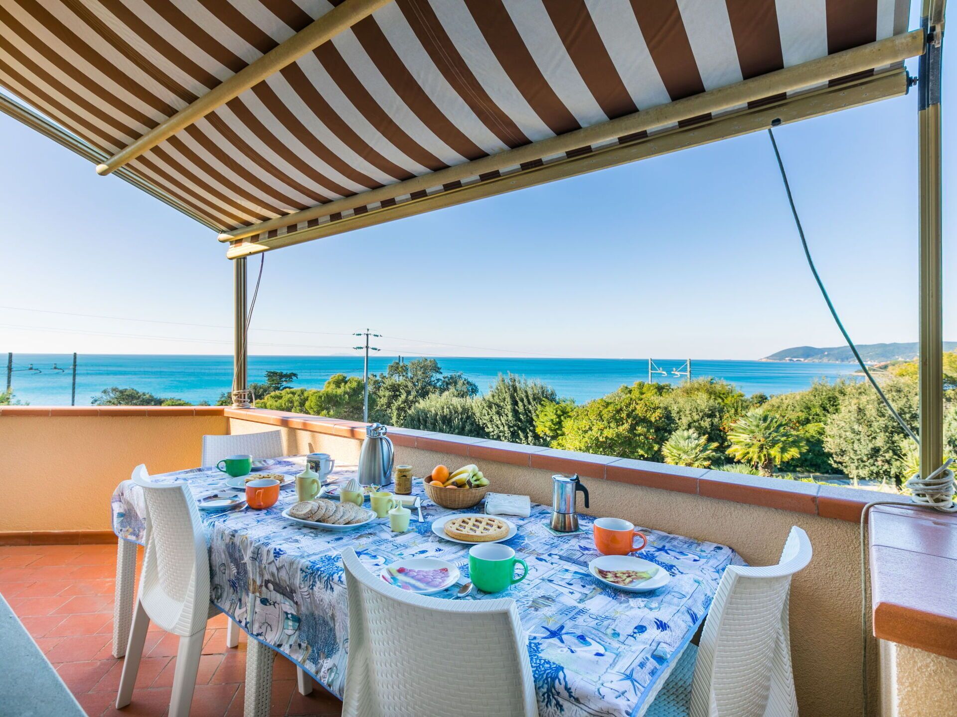 Un balcon avec une table dressée pour le petit-déjeuner, offrant une vue sur la côte.