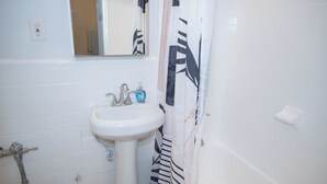 Un bagno con lavandino bianco, specchio e tenda della doccia.