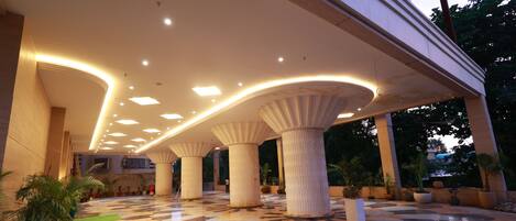 A spacious lobby with a patterned floor, large columns, and recessed lighting.