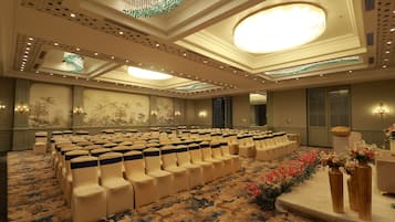 A conference room with rows of chairs, a patterned carpet, and decorative wall panels.
