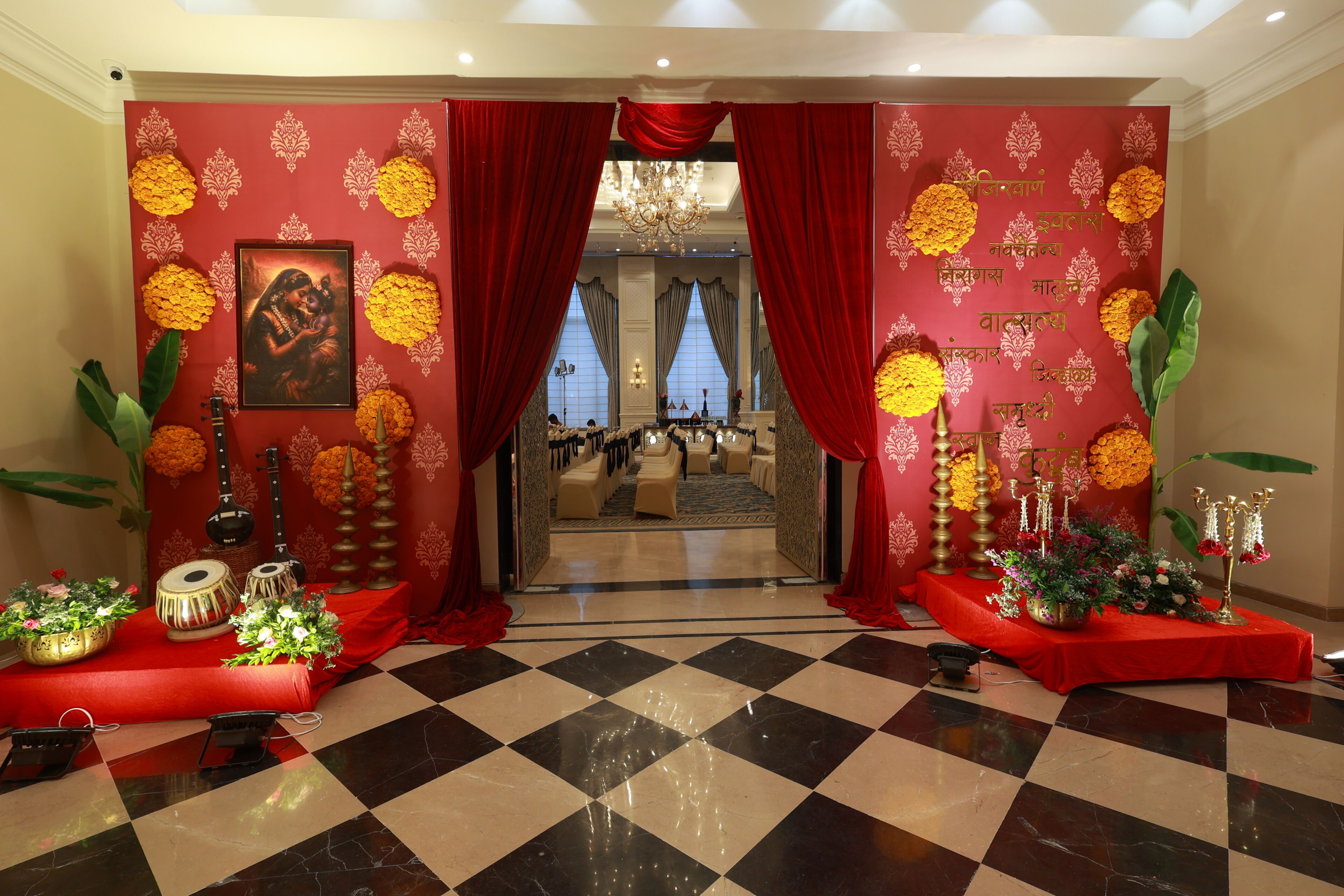 A hotel lobby with a checkered floor, red curtains, and floral decorations.