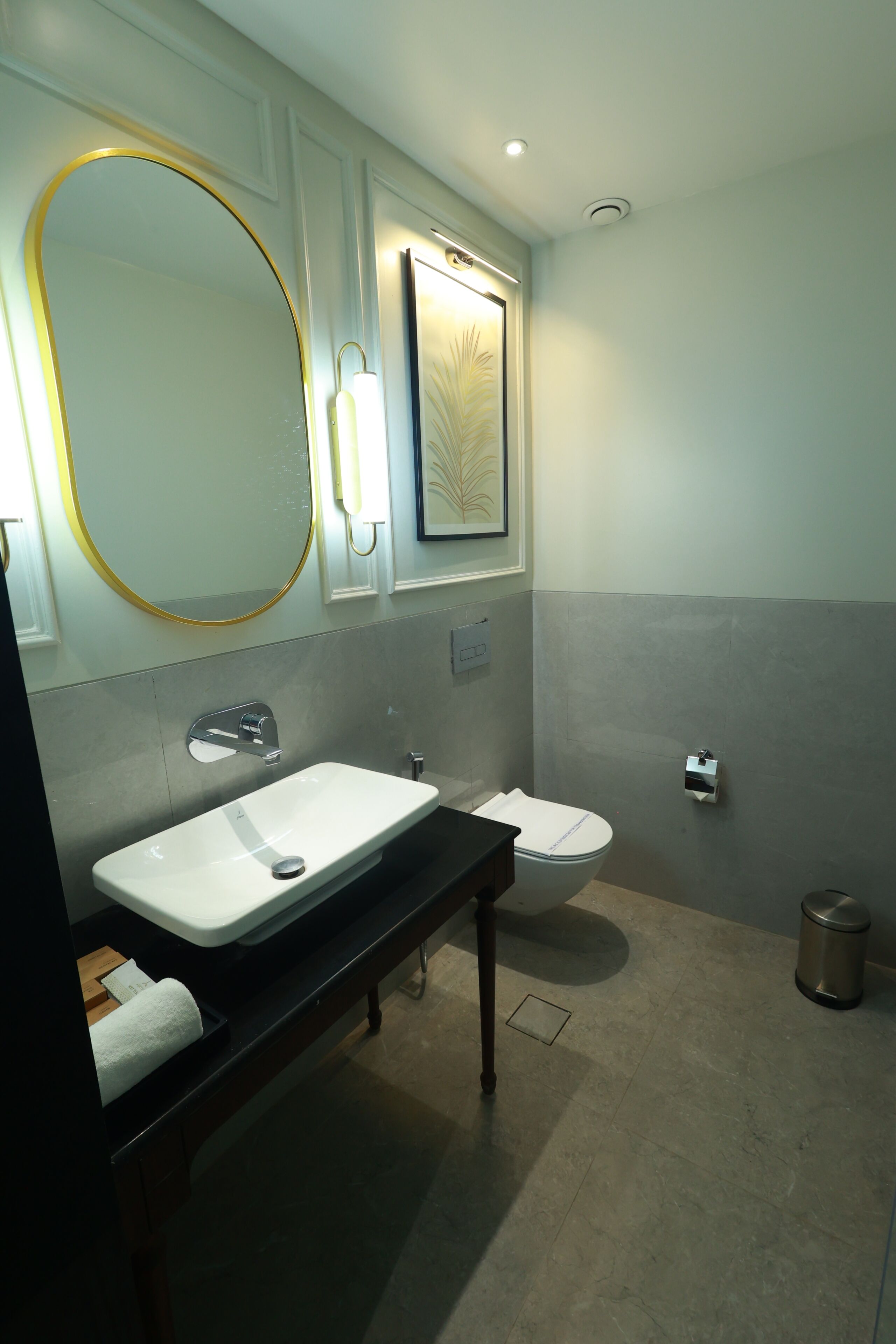 Ein Badezimmer mit großem Spiegel, Waschbecken, Toilette und Mülleimer.