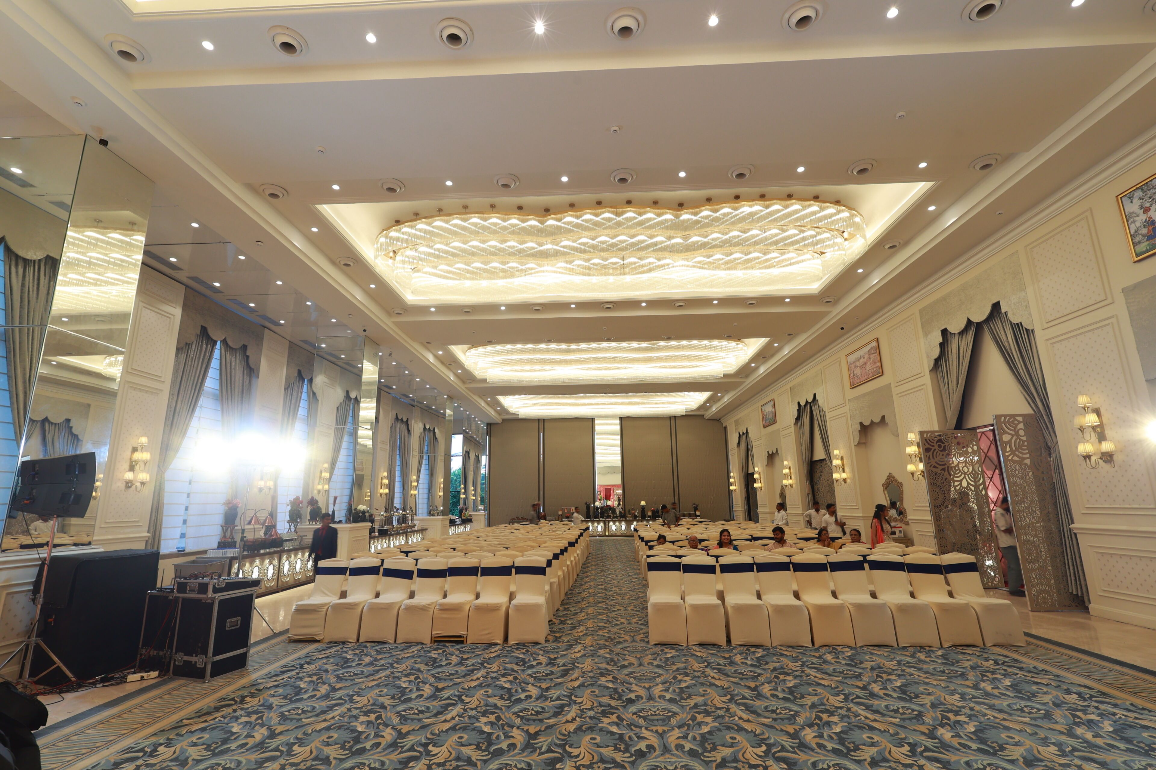 Un amplio salón de conferencias con filas de sillas, una alfombra estampada e iluminación empotrada en el techo.