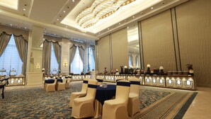 A hotel lobby with a grand chandelier, a reception desk, and a seating area with chairs. - Aurtus (Amravati)