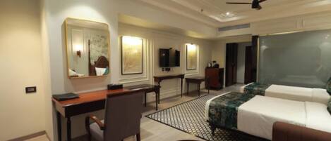 A hotel room with a bed, a desk, a chair, a TV, and a large mirror.