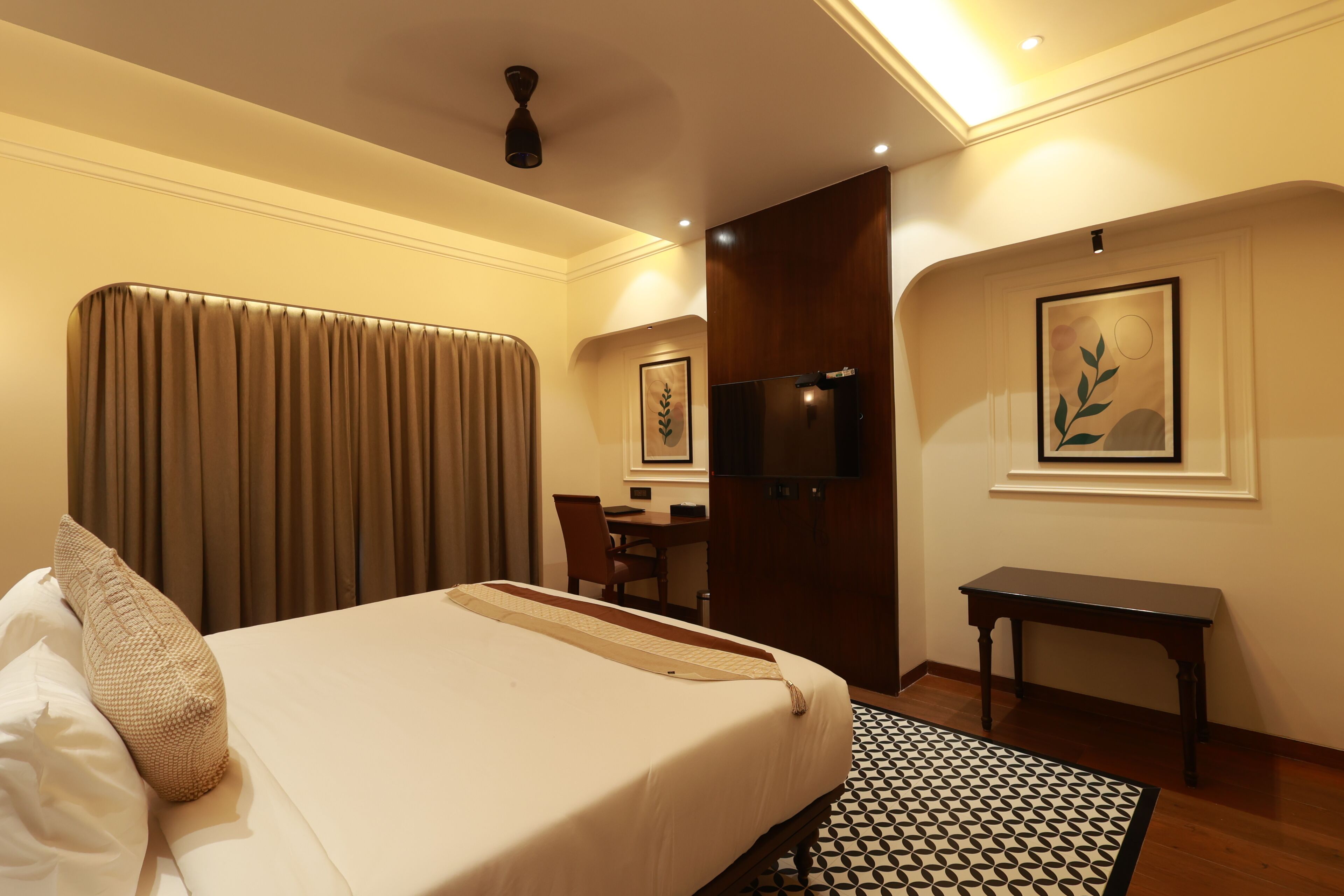 A hotel room with a bed, a desk, a chair, a television, and a framed picture on the wall.