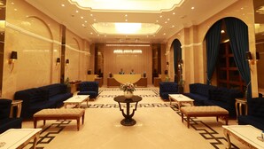 A hotel lobby with a central reception desk, seating arrangements, and a chandelier. - Aurtus (Amravati)