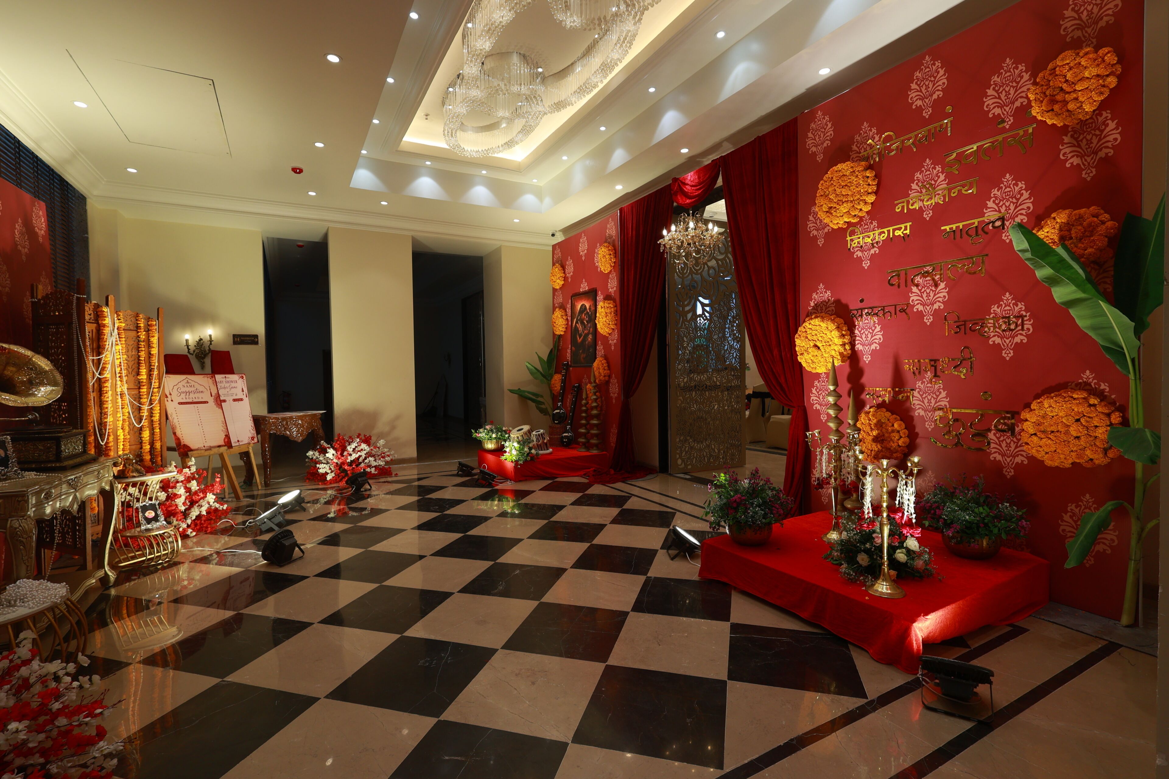Un vestíbulo de hotel con piso de cuadros, decoración en rojo y dorado, candelabros y una mesa de recepción.