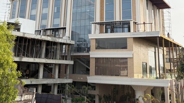 Un edificio de varios pisos con un llamativo frente de vidrio, un atrio central y una terraza en la azotea.