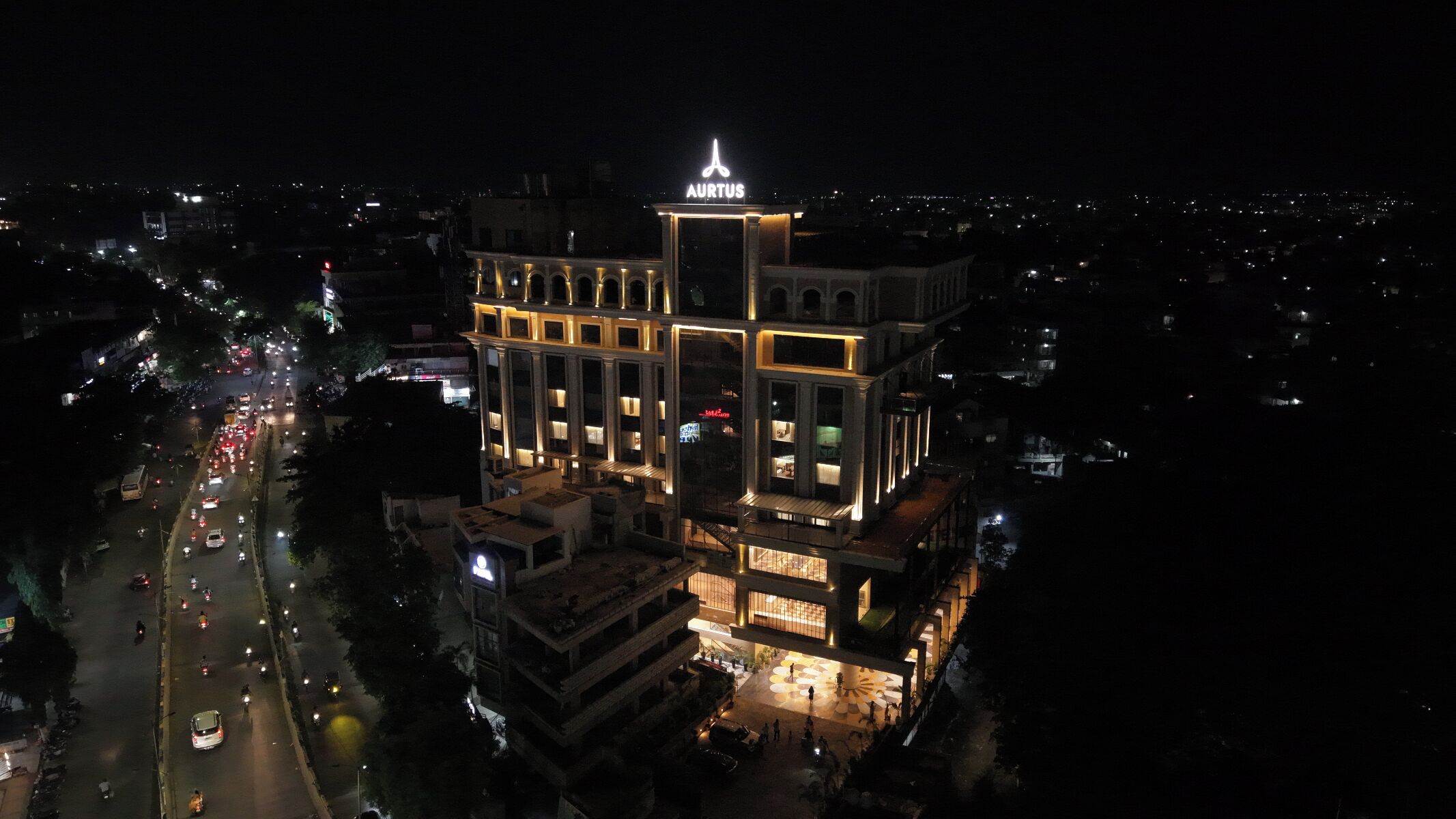 A multi-story building with a prominent sign at the top, surrounded by a busy street at night.