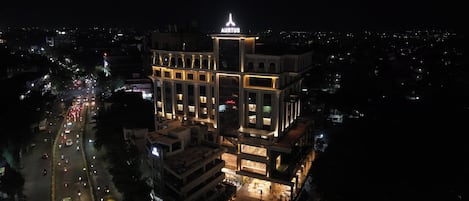 A multi-story building with a prominent sign at the top, surrounded by a busy street at night.