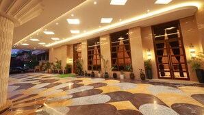A hotel lobby with a patterned floor, large windows, and multiple light fixtures. - Aurtus (Amravati)
