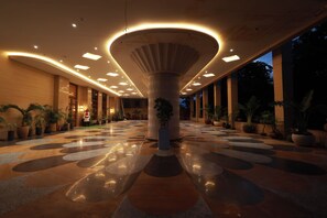 A spacious lobby with a central column, potted plants, and a patterned floor. - Aurtus (Amravati)