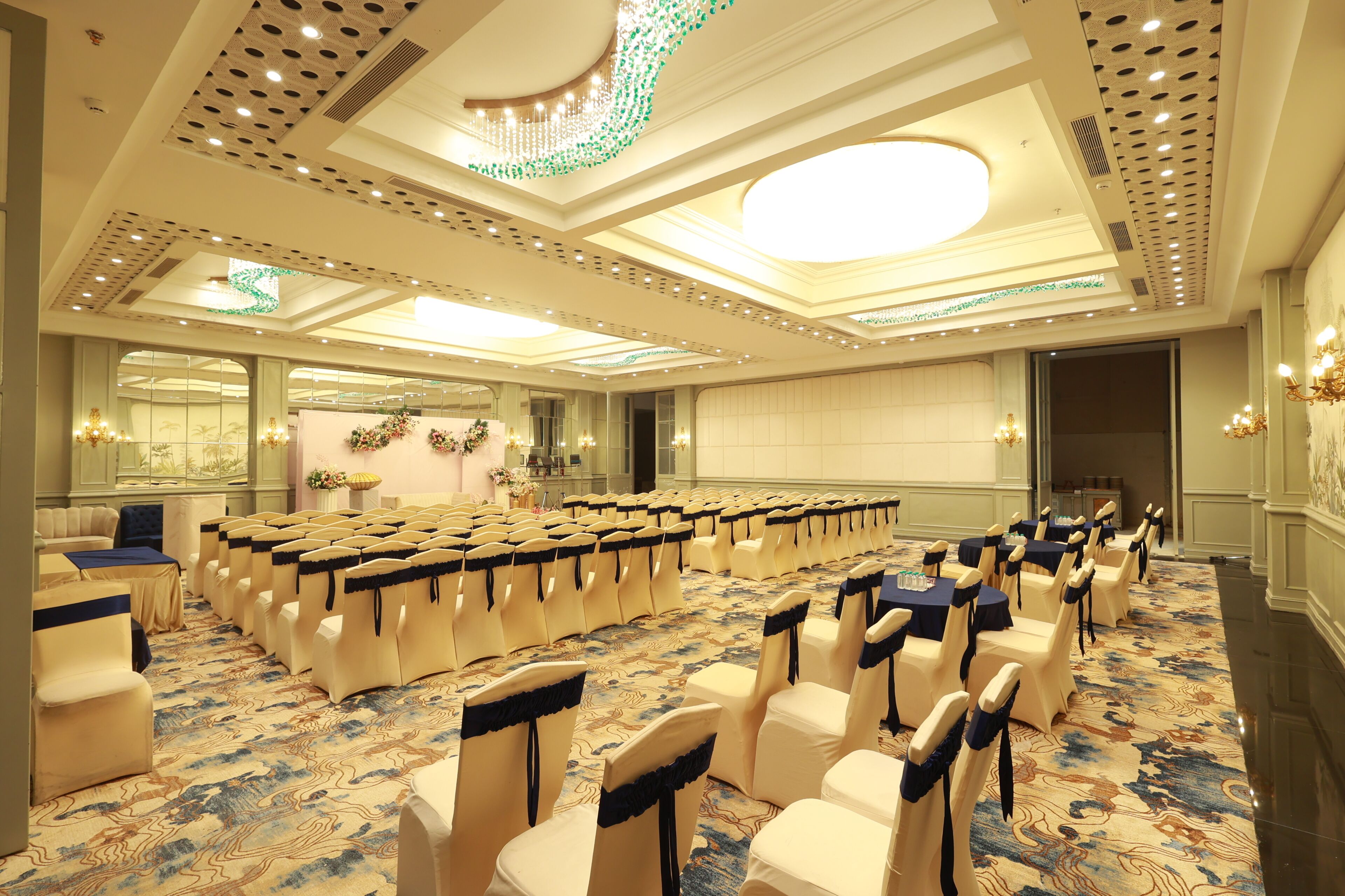 Un salón de conferencias con filas de sillas, una alfombra estampada y un techo decorativo.