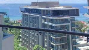 A balcony with a view of the sea and buildings.