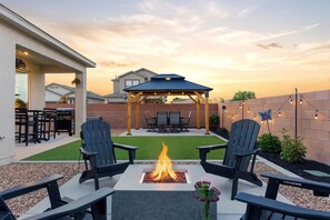 Une terrasse dotée d’un foyer, de fauteuils Adirondack, d’un belvédère et d’une guirlande lumineuse.