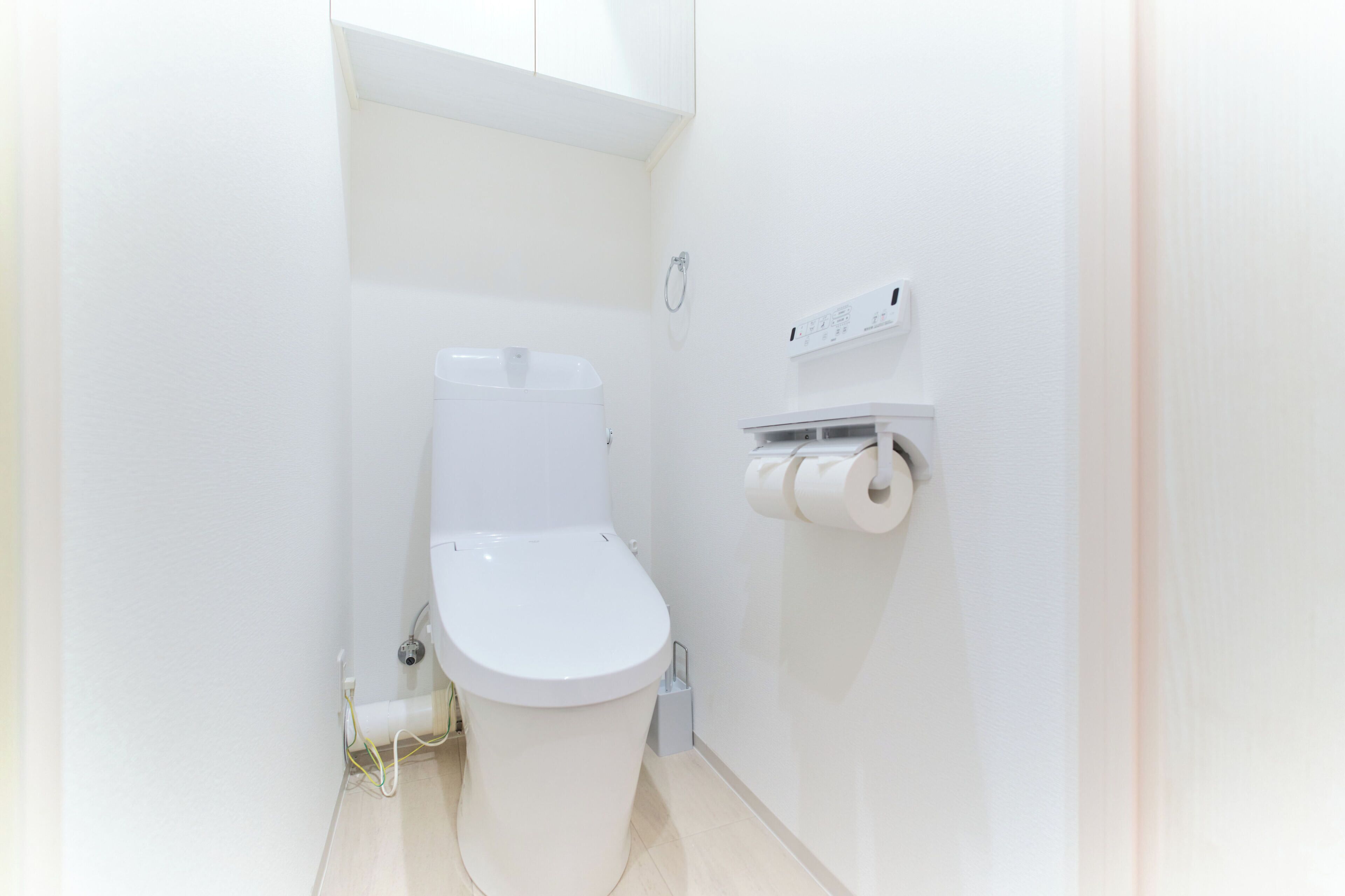 Un baño pequeño y blanco con inodoro, dispensador de toallas y porta papel.