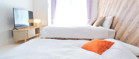 A hotel room with a bed, a TV, a bedside table, and a window with curtains.