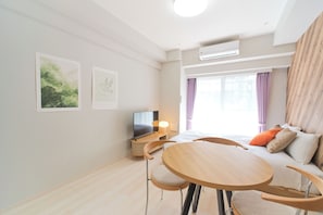 A modern hotel room with a bed, a TV, a dining table, and chairs. - Sarcosuchus Higashikomagata (Tokyo)