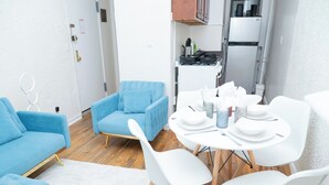 Un espace de vie compact comprenant un canapé bleu, un fauteuil bleu et une table à manger pour quatre personnes.