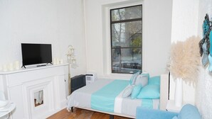 Une chambre à coucher avec un lit, une télévision, un radiateur et une fenêtre.