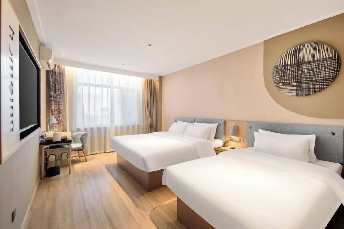 Hotellihuone, jossa on kaksi sänkyä, työpöytä ja televisio.