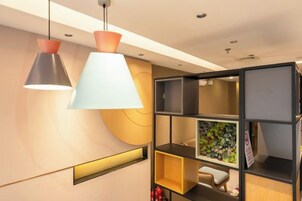 Un interior moderno con iluminación colgante, una estantería de pared y un pequeño rincón de estar.