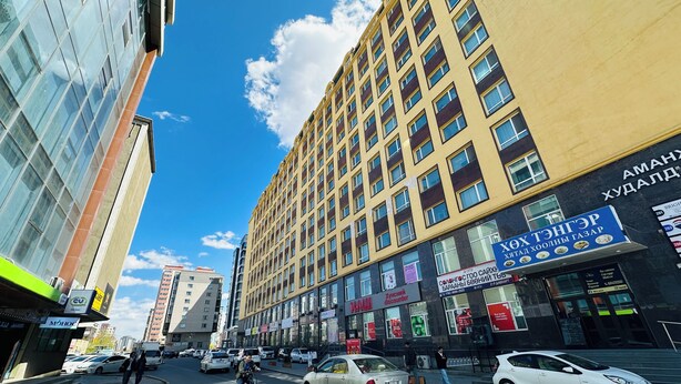 Un edificio de varios pisos con locales comerciales en la planta baja, incluyendo un restaurante y una tienda de descuento.