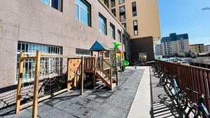 Un edificio con un parque infantil, un aparcamiento para bicicletas y un sendero peatonal.