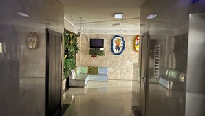 Un pasillo con un banco, un televisor y un adorno en la pared.