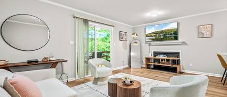 Un salon comprenant un canapé, des fauteuils, une table basse, un téléviseur et une cheminée.