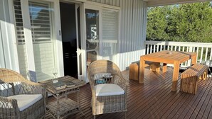 A wooden deck with wicker furniture, a table, and chairs.
